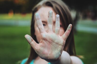 Mujer con brazo estirado y mano en señal de alto Emprender también tiene género Enlaza Consultoría de Género y Diversidad